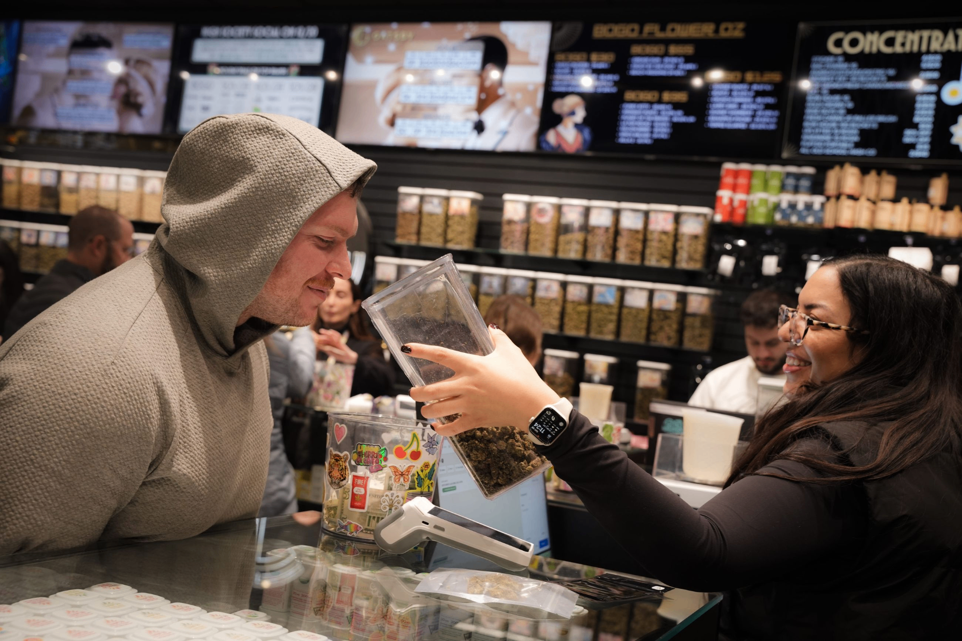 Budtender handing a jar of cannabis flower to a customer at the Gatsby dispensary counter